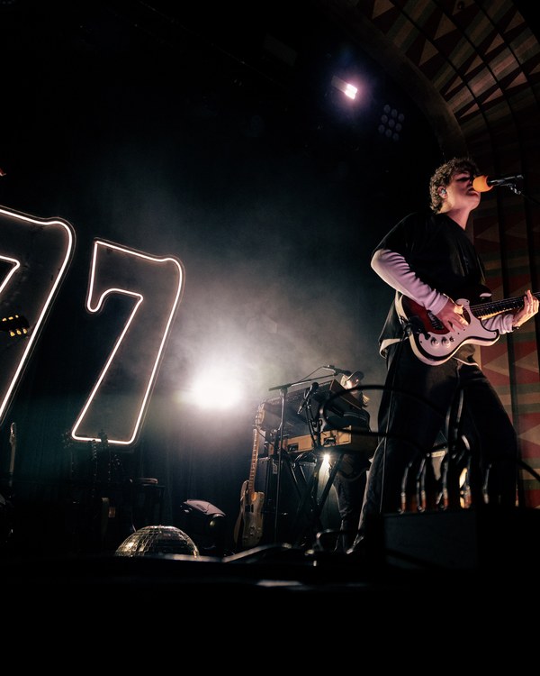 Colony 4 live on stage beside a giant neon 77